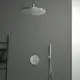 Duschelement mit runder Kopfbrause und Handbrause an grauer Wand. Steuerungseinheit mit drei Reglern. Ideal Standard Design, schlicht gehalten, integriert in modernen Raum.